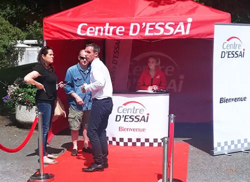 Une hôtesse souhaite la bienvenue aux clients au stand d'accueil Centre d'Essai Driving