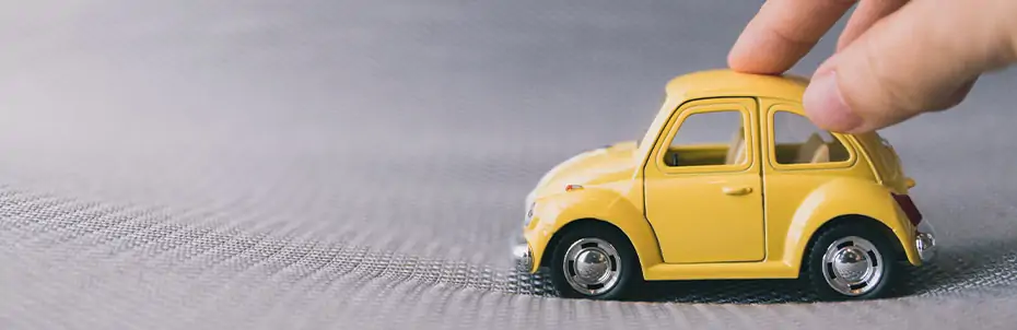 Une personne fait rouler une voiture miniature jaune